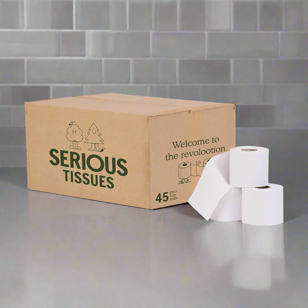 Cardboard box labeled ‘Serious Tissues’ with green branding and the message ‘Welcome to the revolootion.’ The box contains 45 eco toilet rolls, with three white recycled toilet rolls displayed in front on a grey countertop with tiled background.